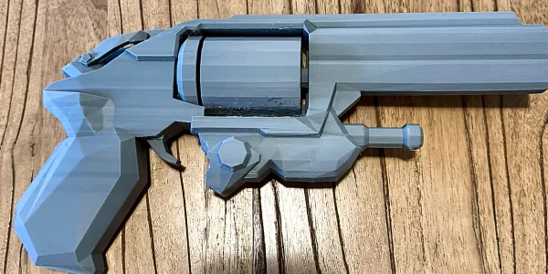 Grey 3D printed low-poly revolver prop on a timber table