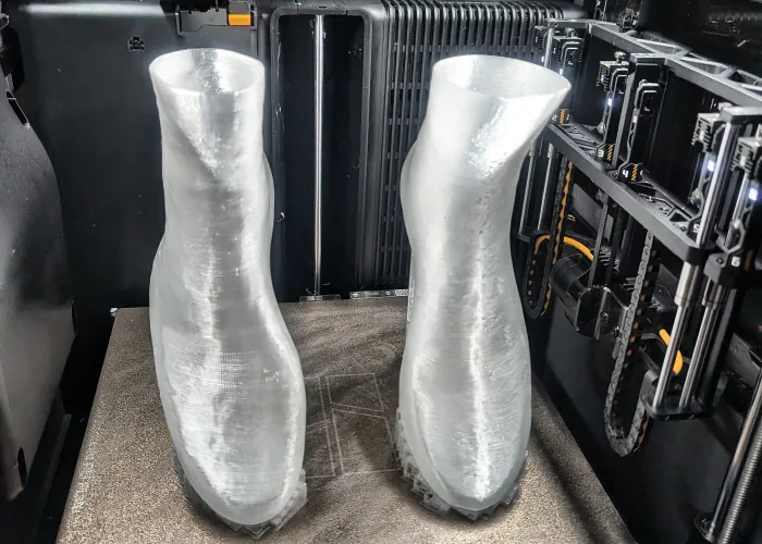 Bambu Lab H2C printer with two translucent printed parts on the build plate