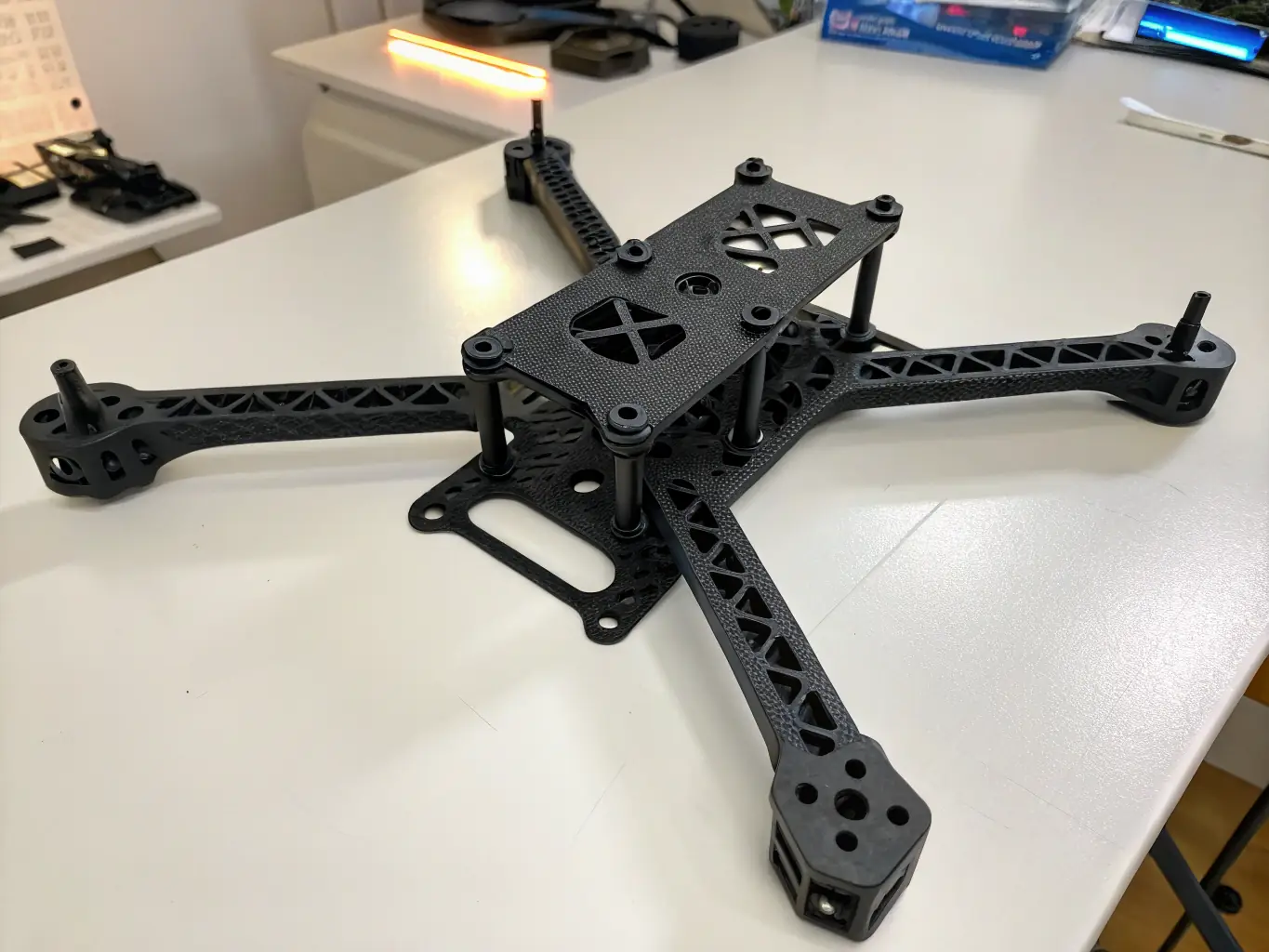 A close-up shot of a carbon fiber 3D printed part, showcasing its intricate design and the texture of the carbon fiber material. The part is a component of a drone, highlighting its lightweight and high-strength properties.